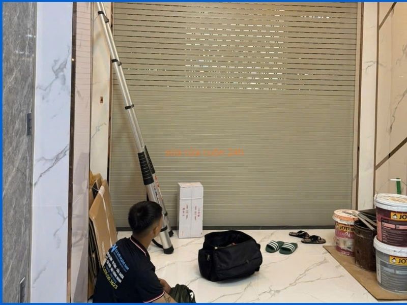 Thợ kỹ thuật đang kiểm tra và sửa chữa cửa cuốn chuyên nghiệp.