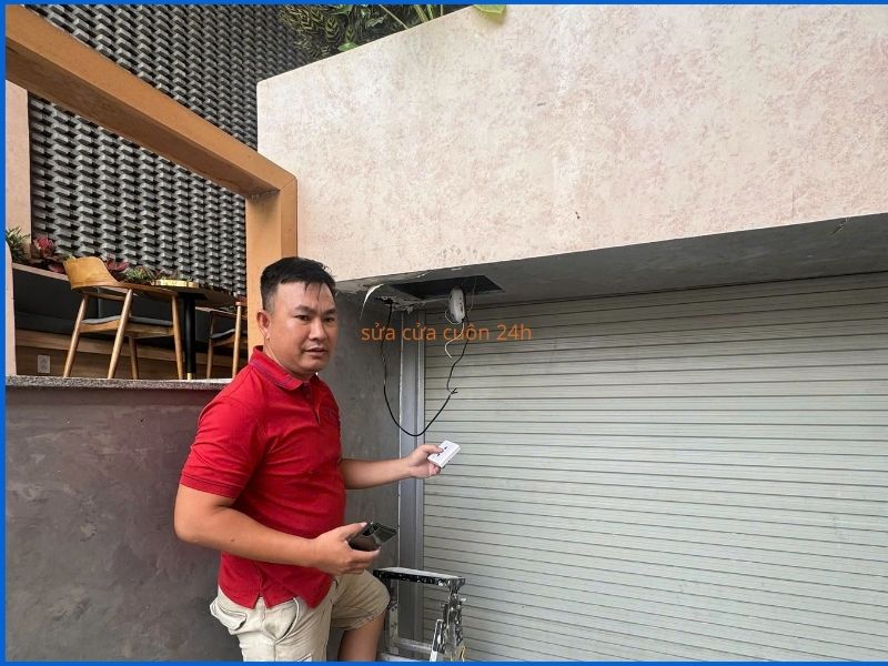 Thợ kỹ thuật đang sửa remote điều khiển cửa cuốn bị lỗi tại nhà